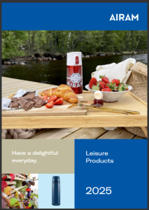 A wooden tray on a dock by a river with a thermos, croissant, strawberries, chocolate, and a small jar of jam, with a soft blanket and greenery in the background. The image promotes AIRAM Leisure Products with a blue and beige design and the text 'Have a delightful everyday.'